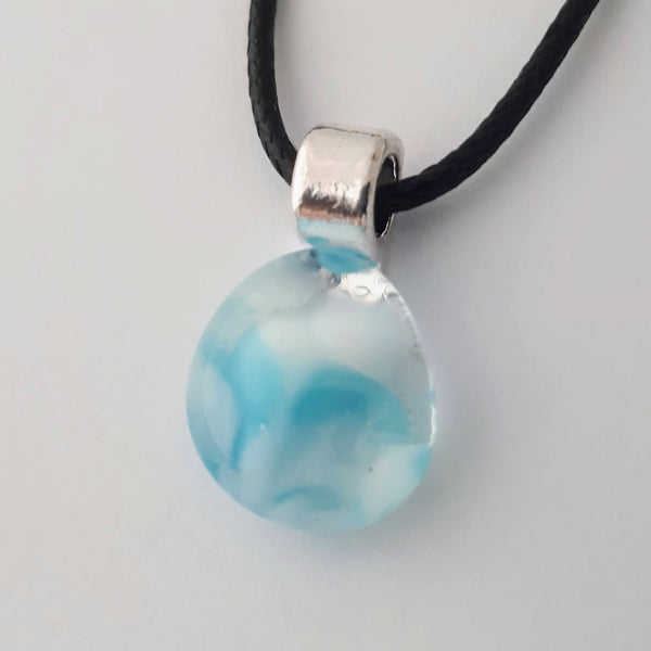 small blue and white oblong glass pendant with silver coloured bail and black cord on white background