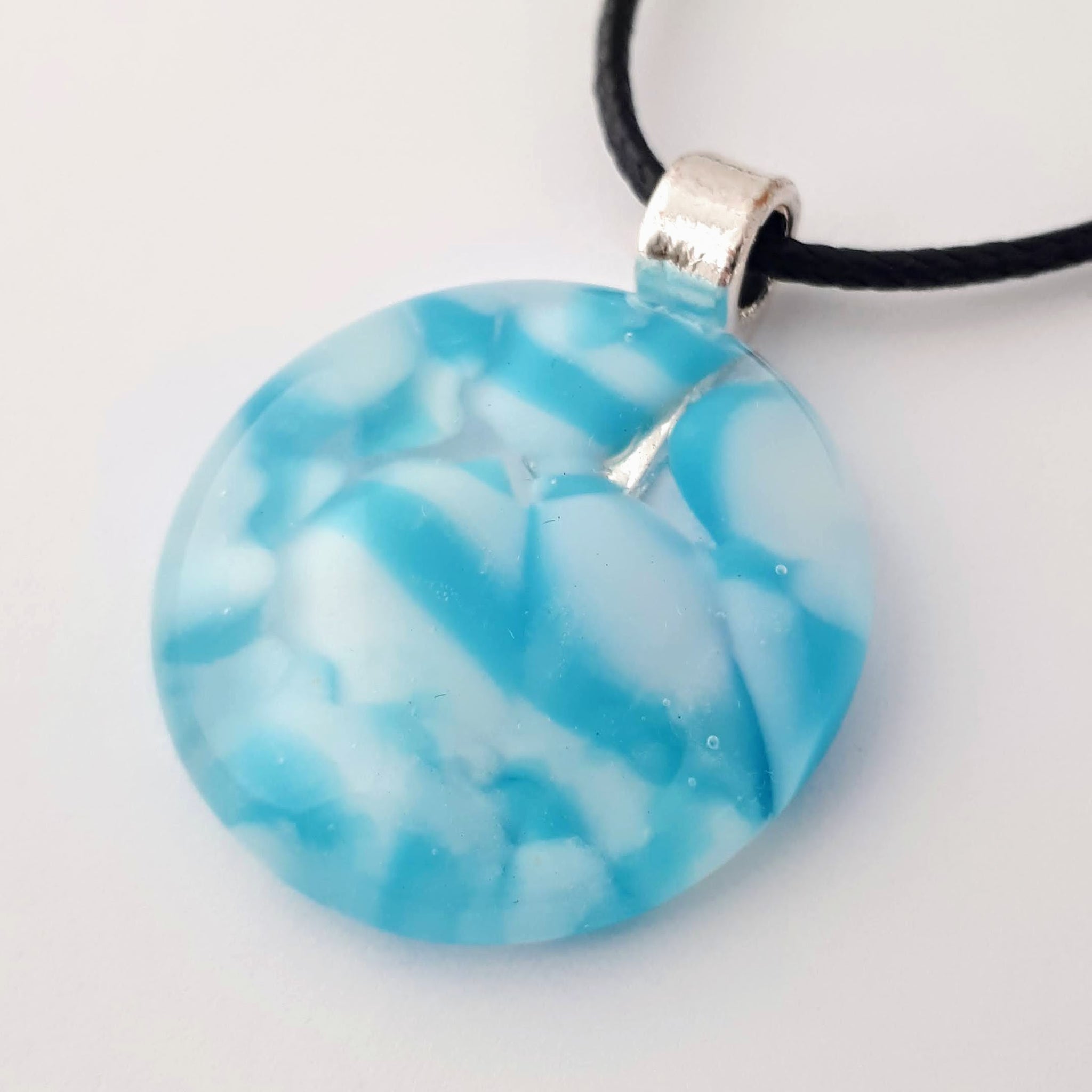 blue and white round glass fused pendant with silver coloured bail and black cord on white background