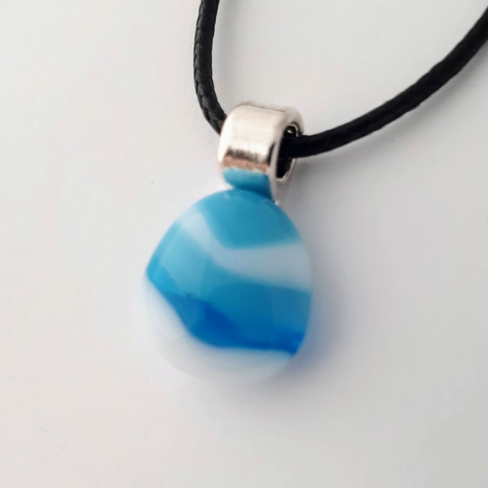 blue and white striped small tear drop glass fused pendant with silver coloured bail and black cord on white background