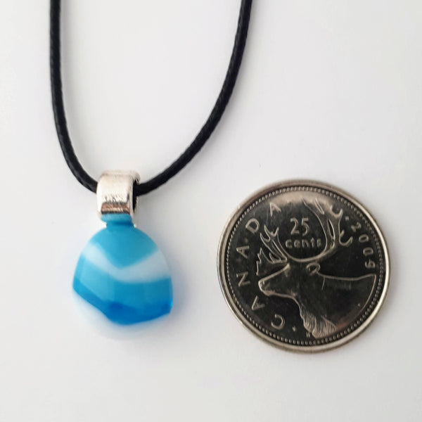 blue and white striped small tear drop glass fused pendant with silver coloured bail and black cord on white background with quarter for scale