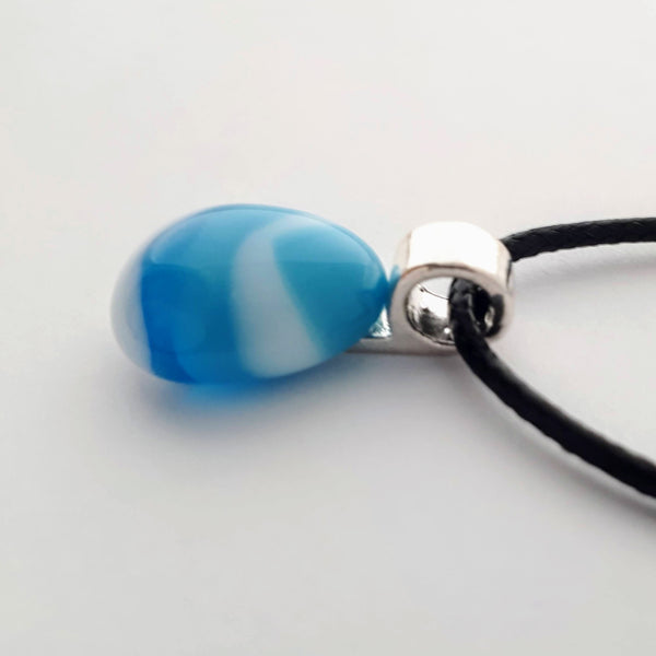 blue and white striped small tear drop glass fused pendant with silver coloured bail and black cord on white background side view